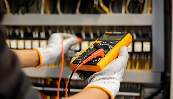 Electrician uses a multimeter to test a commercial electrical installation control panel