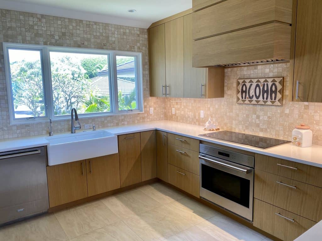 After - beautifully remodeled kitchen with farmhouse sink, new cabinets, and Aloha sign.