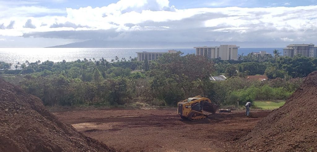 Maui excavation contractor and worker with hills of soil on a new home project.