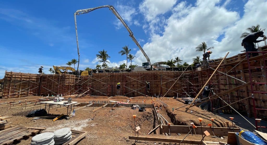 Image of a crane pouring concrete for a home's first floor 12-foot concrete retaining wall