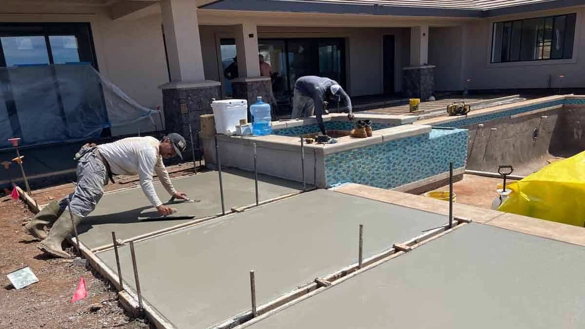 Image of Crescent Homes Maui cement worker installing and smoothing a cement walkway