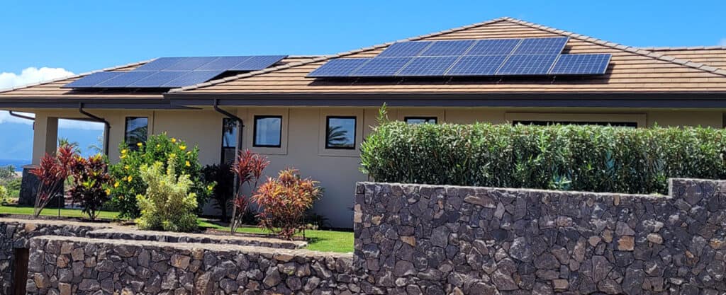 A new Maui home with solar water heating system on the roof and a stone retaining wall.